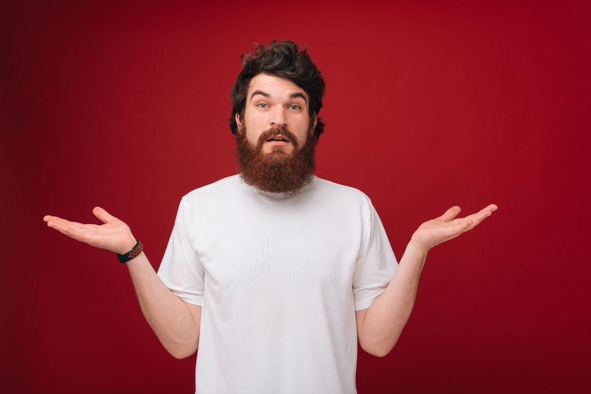 Who knows. It's not me. Portrait of confused handsome man giving I dont know gesture on red background